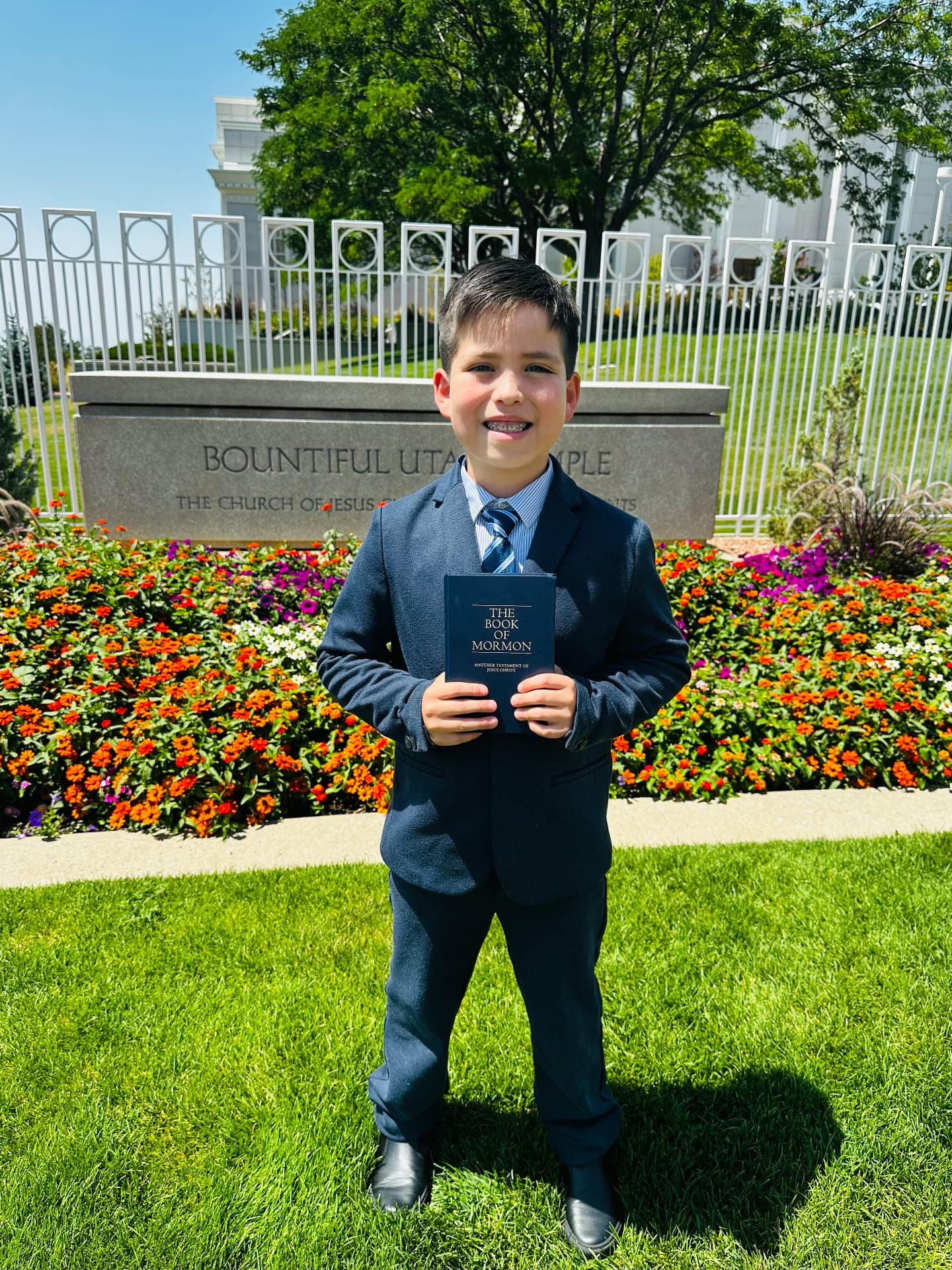 Oliver Anthony Martinez smiling and holding the Book of Mormon outside the Bountiful Utah Temple.