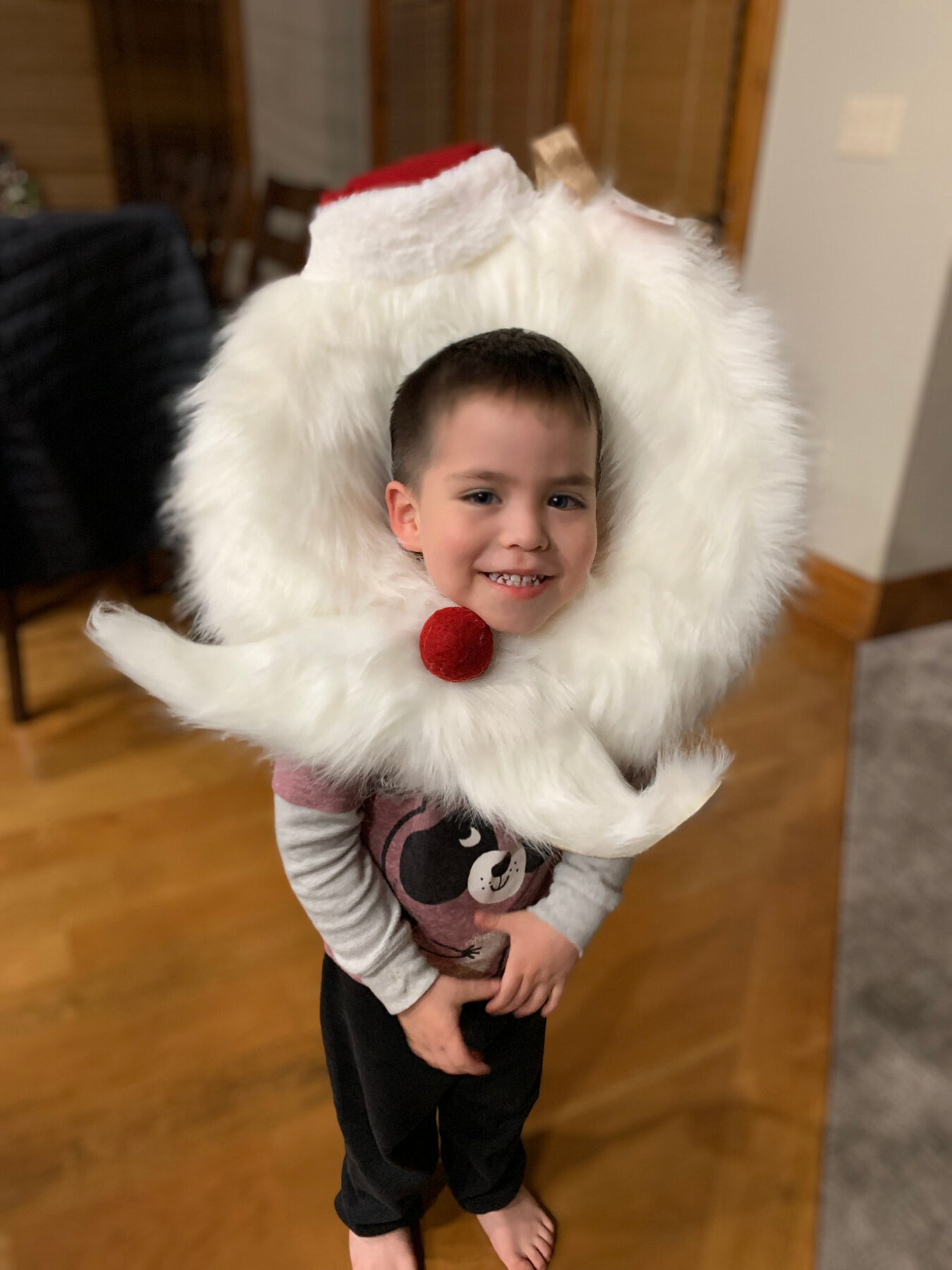 Young Oliver smiling inside a fluffy Santa beard.