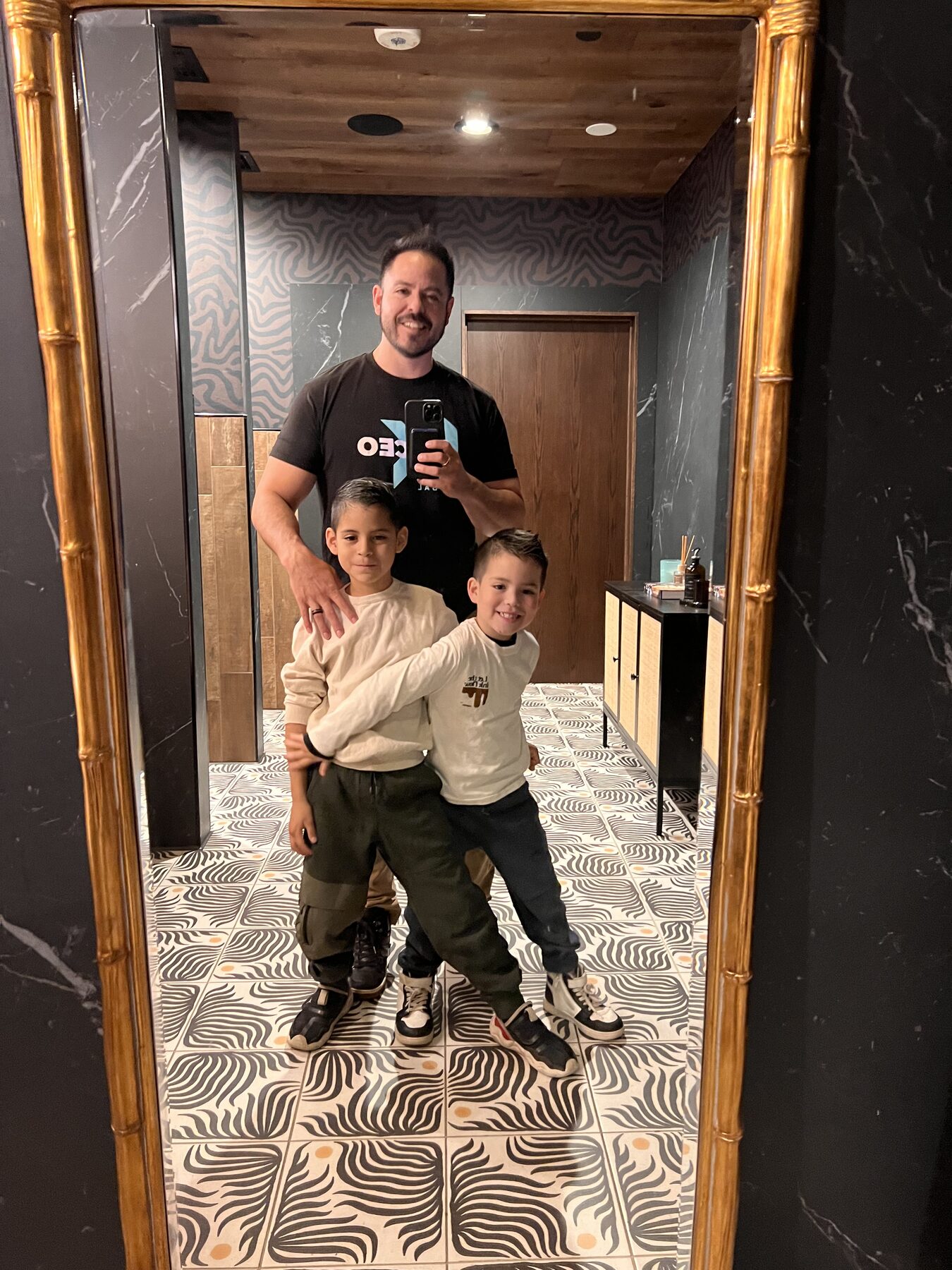 Oliver posing playfully with his family in an elevator mirror.
