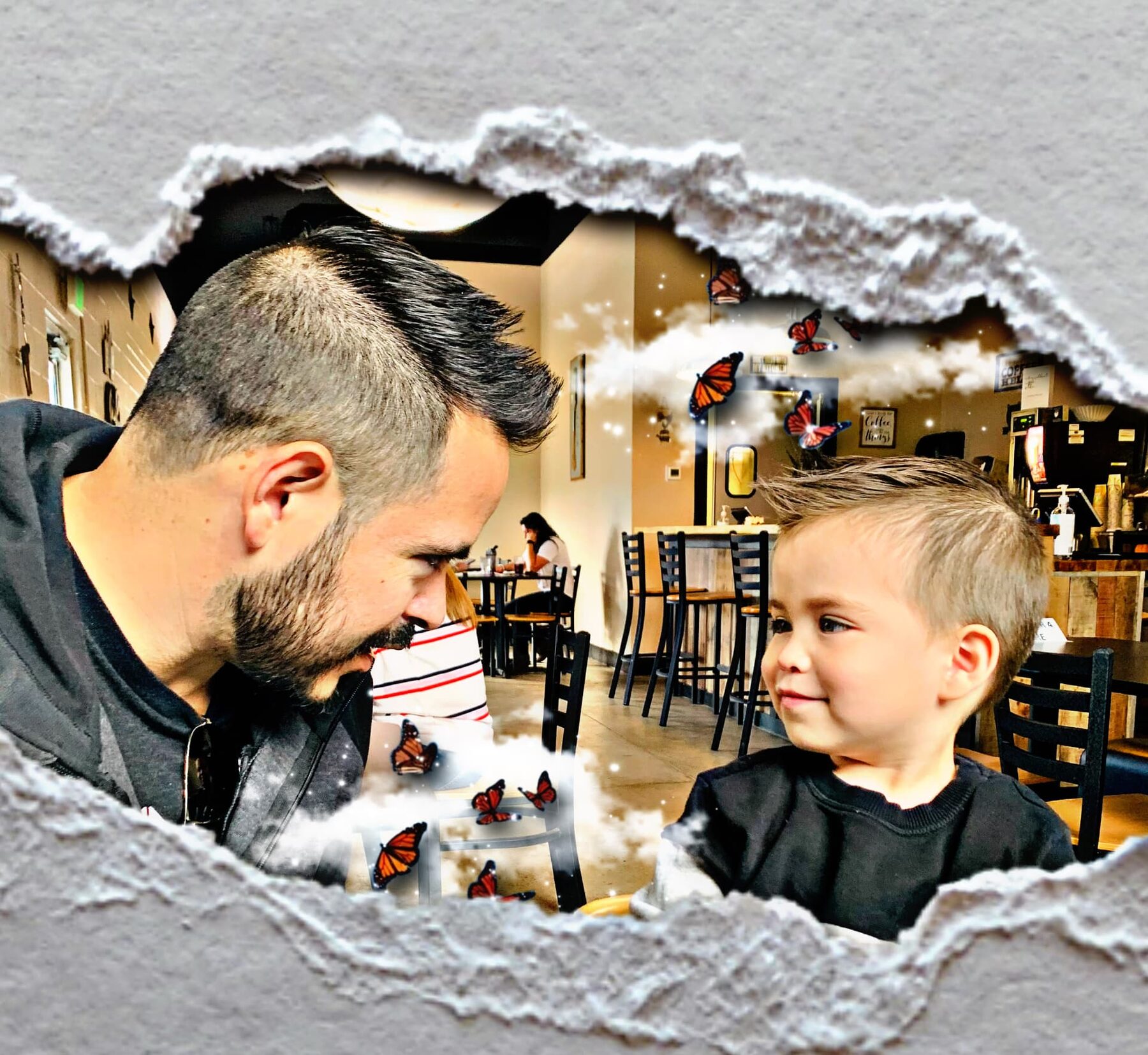 Young Oliver smiling at his dad across a table.