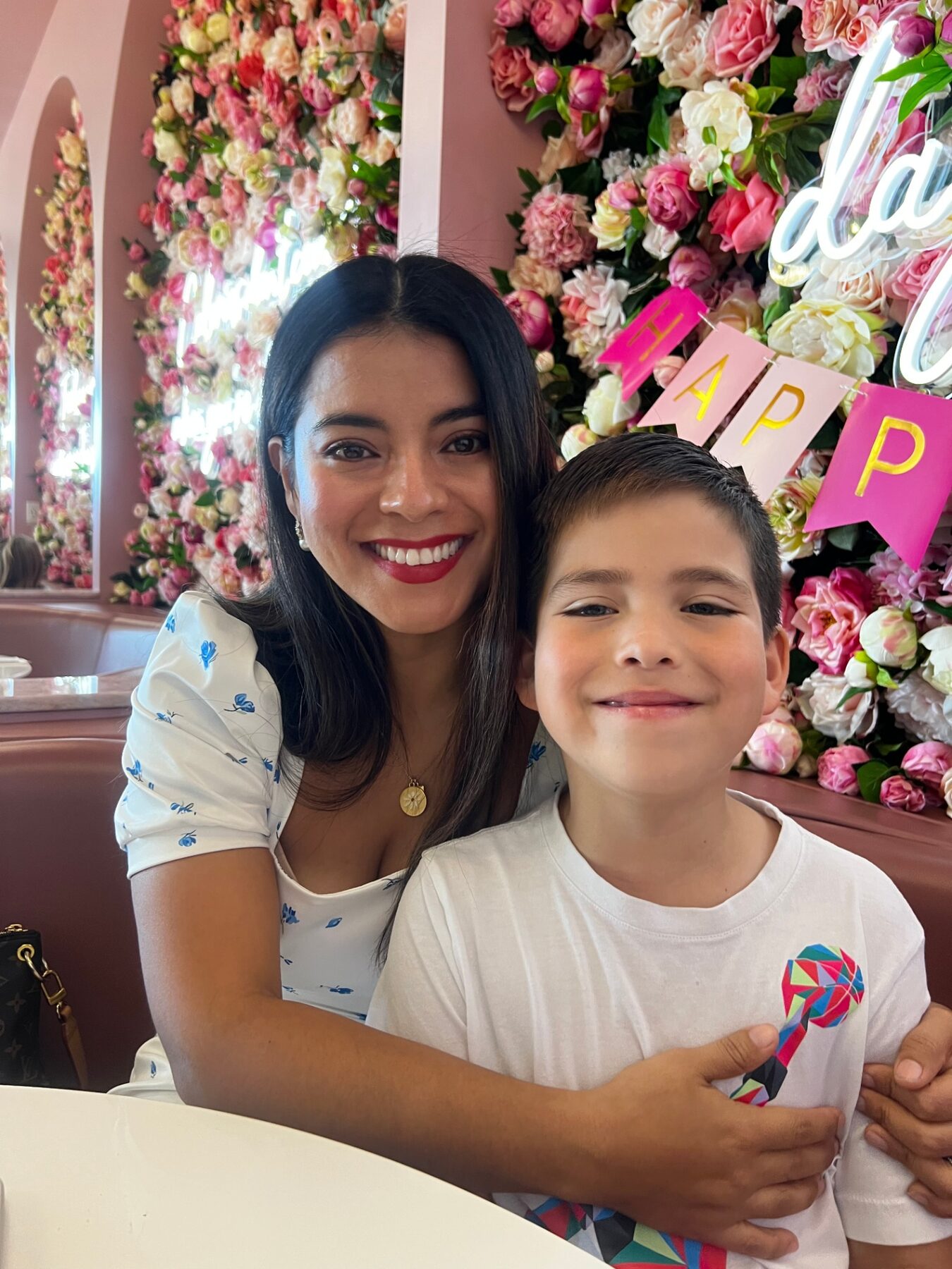 Oliver smiling with his mom at a flower-filled celebration.