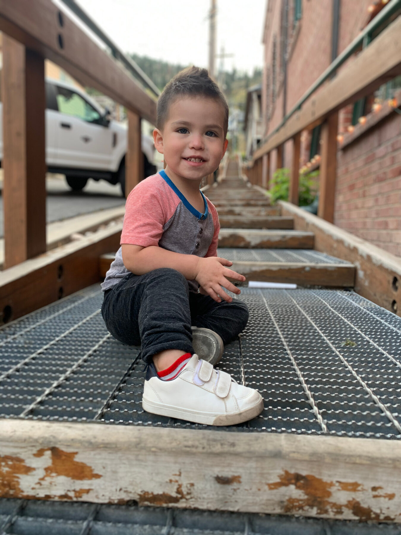 Toddler Oliver smiling while sitting on outdoor steps.