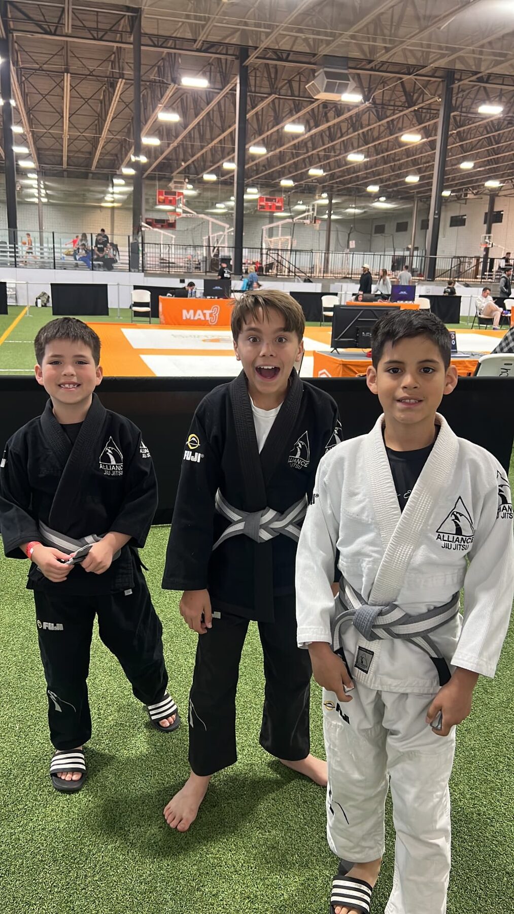 Oliver smiling with two friends at a jiu-jitsu competition.