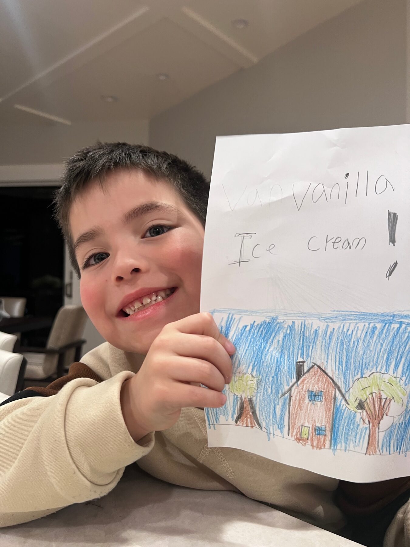 Oliver proudly holding up a drawing of a house and ice cream.