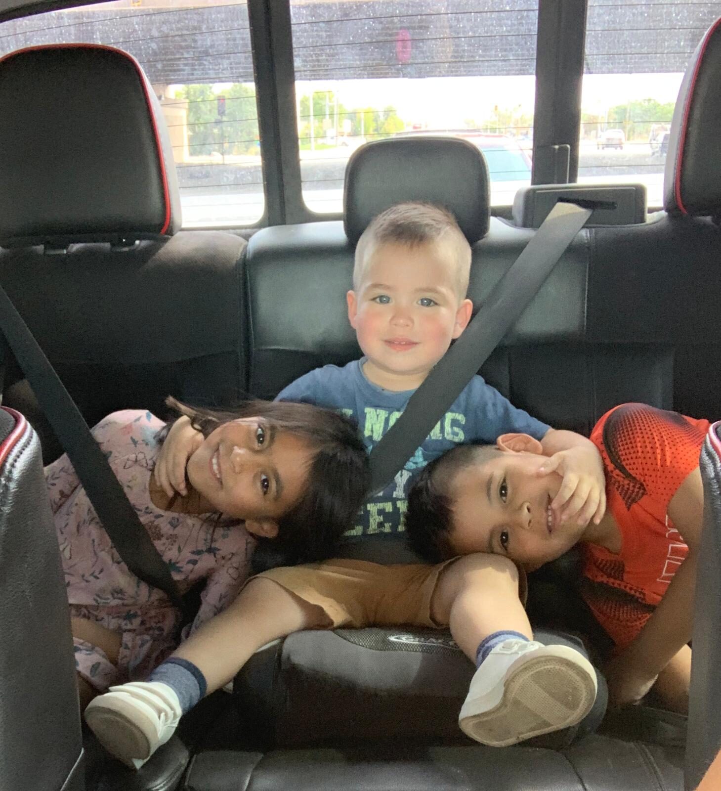 Young Oliver sitting between his sister and brother in the car.