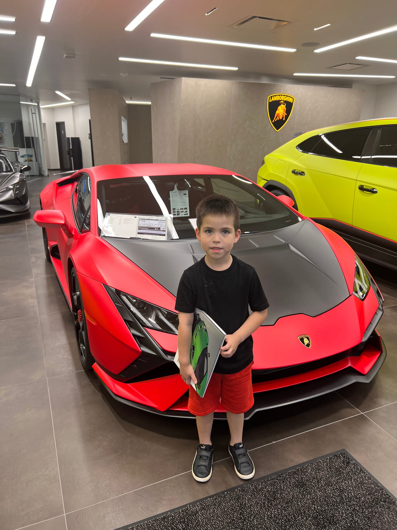 Oliver standing beside a red sports car at a showroom.